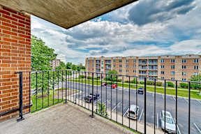 A view from a balcony overlooking a parking lot and apartment buildings.