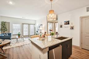 A kitchen with a granite countertop and a blue sofa in the living room.