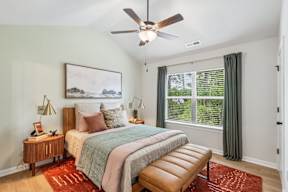 A bedroom with a bed, nightstand, and window.