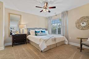 A bedroom with a bed, nightstand, and a ceiling fan.