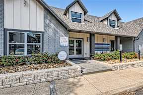 the front of a gray house with a sidewalk in front of it