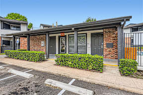 a small brick building with a gray door and a sidewalk