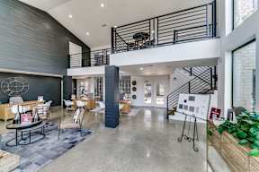 the lobby of a building with a staircase and tables and chairs
