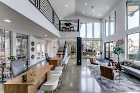 the living room and dining area of a house with large glass windows and a staircase
