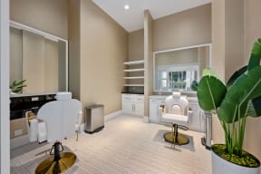 a living room with white chairs and a desk and a window