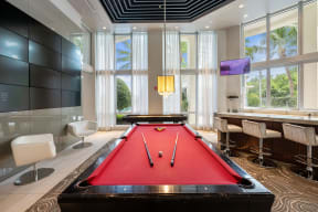a red pool table in a room with a bar and windows