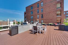 A wooden deck with chairs and a table in front of a red brick building.