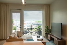 a living room with a couch and a television and a balcony