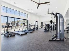 A spacious gym with treadmills, elliptical machines, and a fan.