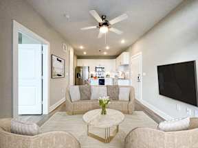 A living room with a beige couch, a coffee table, and a ceiling fan.