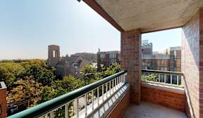 A balcony with a green railing overlooks a cityscape.