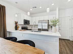 A kitchen with a wooden table and black chairs.
