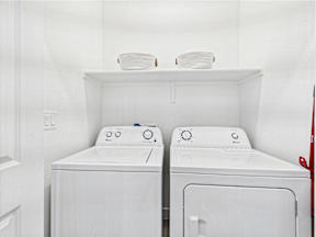 Two white front loading washing machines in a laundry room.