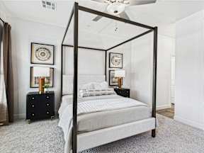 A four poster bed with a white bedspread and a white pillow.