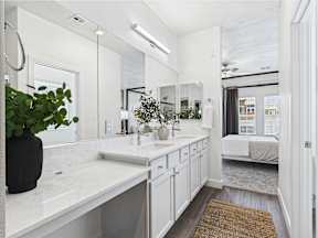 A bathroom with a white countertop and a brown rug.