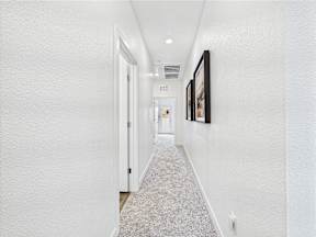 A hallway with white walls and a carpeted floor.