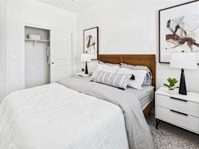 A bedroom with two beds and a nightstand with a lamp.