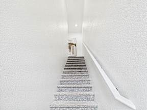 A staircase with a white handrail leading to a door.