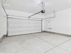 A garage with a white door and a grey floor.