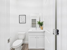 A white bathroom with a toilet, sink, and a plant.