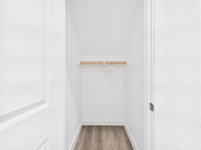 A white hallway with a coat rack and wooden floor.