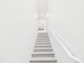 A staircase with a white handrail and grey steps.