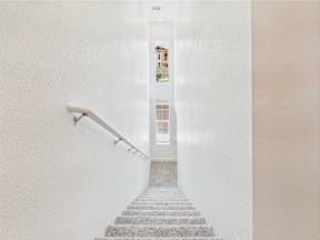 A staircase with a white wall on either side and a poster on the wall.