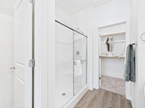 A white bathroom with a walk in shower and a towel rack.
