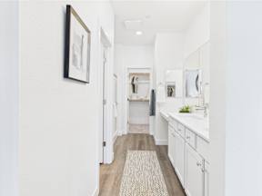 A bathroom with white cabinets and a rug on the floor.