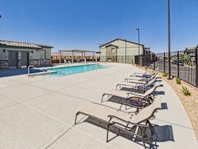 A pool with sun loungers and a building in the background.