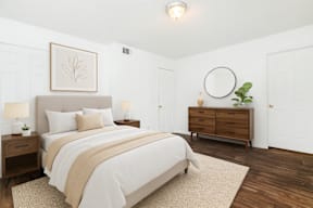 A bedroom with a large bed, a nightstand, and a dresser.