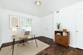 A room with a desk and a chair with a laptop on it.