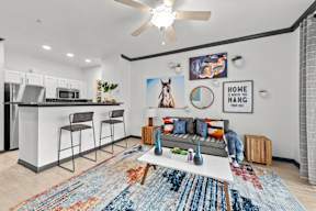 A modern kitchen with a bar area and a living room area with a couch and a rug.