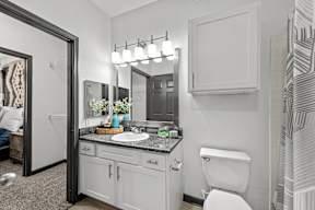 A bathroom with a white toilet, a sink with a mirror above it, and a shower area.
