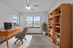 A room with a desk, chair, and bookshelf.