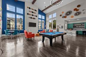 A pool table is in the middle of a room with a blue wall and a television.