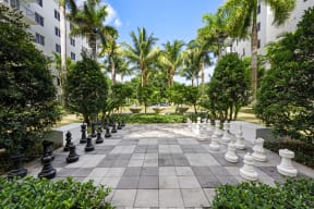 a large chess set in the middle of a courtyard with palm trees