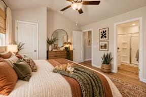 A bedroom with a bed, a ceiling fan, and a cat on the bed.