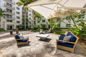 a patio with chairs and an umbrella in front of an apartment building