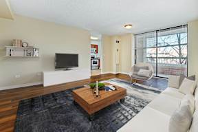 A living room with a white couch, a wooden coffee table, and a flat screen TV.