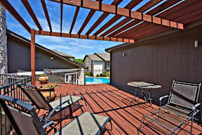 a covered deck with a pool and patio furniture