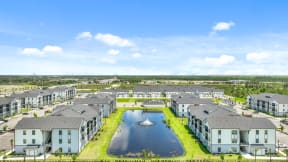an aerial view of an apartment complex with a fountain in the pond