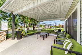 A patio with a white roof and green couches.
