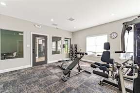 A well-lit home gym with a variety of exercise equipment.