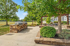A park area with a fire pit and picnic tables.