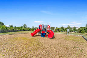 A playground with a red slide and a blue structure.