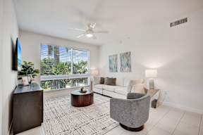 A living room with a white couch, a grey armchair, and a wooden coffee table.