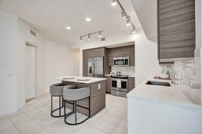 A modern kitchen with a bar area and a microwave above the stove.