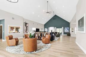 A living room with a rug, chairs, and a ceiling fan.