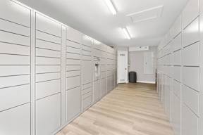 A long hallway with white lockers on the side and a door at the end.